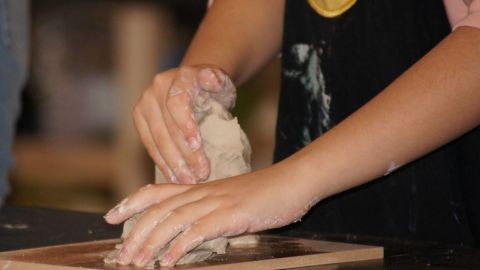 Hands moulding clay into something.