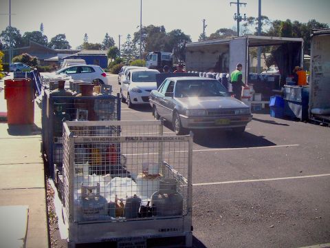 Cars in carpark full of containers with different items like paint and gas bottles