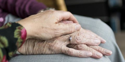 A close up of a younger hand on an older person's hand.