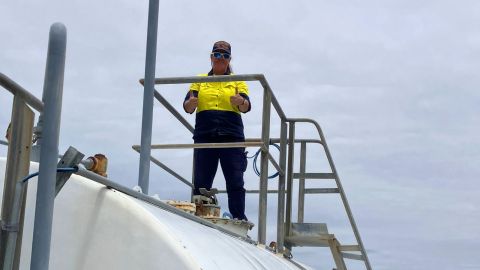 a woman standing on top of a fuel tank giving thumbs up