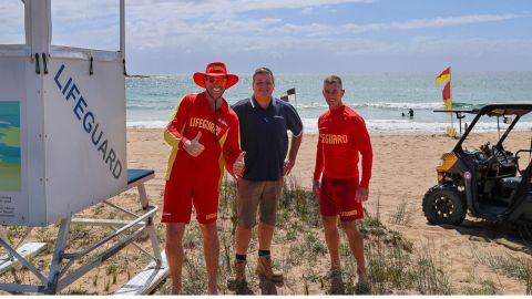 Two lifeguards and a council worker standing on the beach next to a lifeguard tower