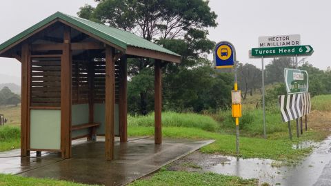 A bus stop next to a road sign pointing to Tuross Head