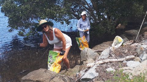 Two landcare volunteers collecting shoreside debris