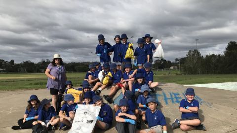 Eurobodalla school students sitting on a ramp at a skate park while holding clean up australia day bags and wearing gloves