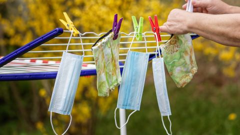 Five face masks on a washing line with yellow flowers in background