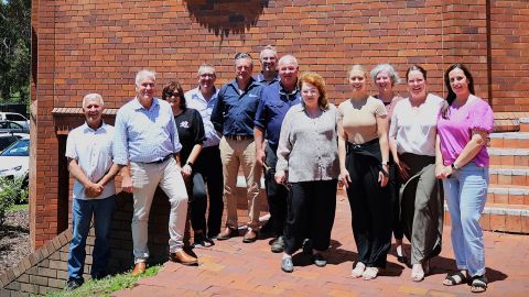 A group of men and women in front of a red brick wall