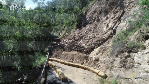 landslide of earth and rocks across section of road on steep hillside