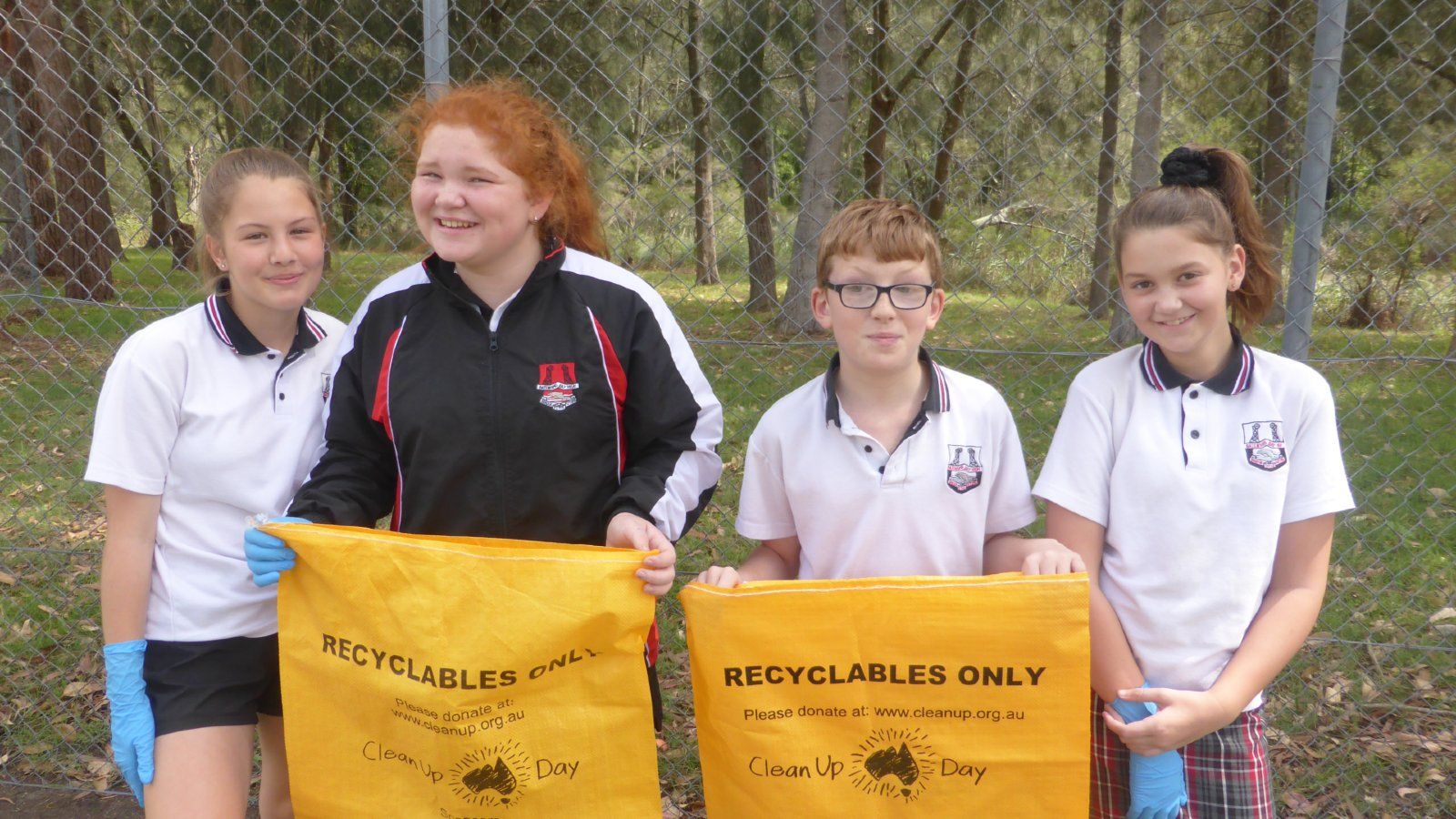 Children standing in a line holding up yellow clean up Australia rubbish bags banner image