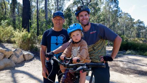 small child on a bike with father and mountain bike club member