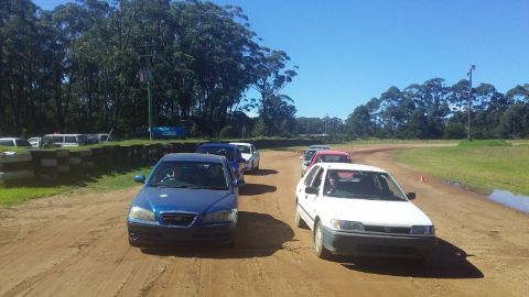 Several cars lined up in two lines on a dirt track.