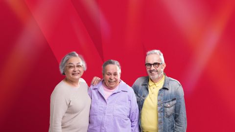 Three senior people smiling and standing in front of a red background.