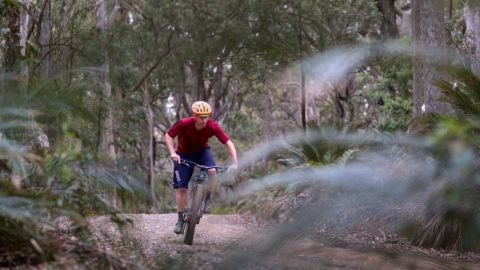 Man in red shirt riding mountain bike on dirt trails