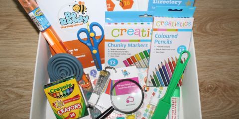 A box of random things for children, including magnifying glass, pencils, bubbles, and pamphlets