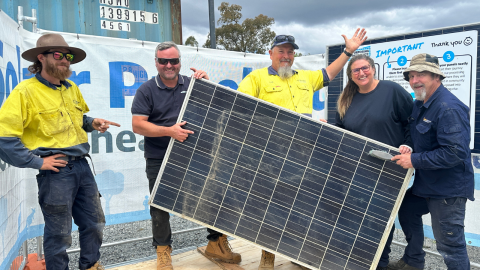 Group of people standing behind a solar panel