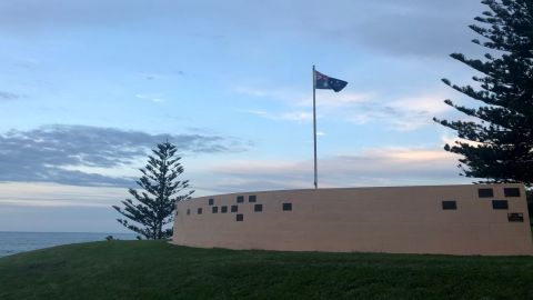 Australian Flag behind low brick wall near ocean