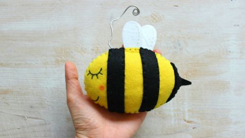 A bee soft toy in the hand of a child.