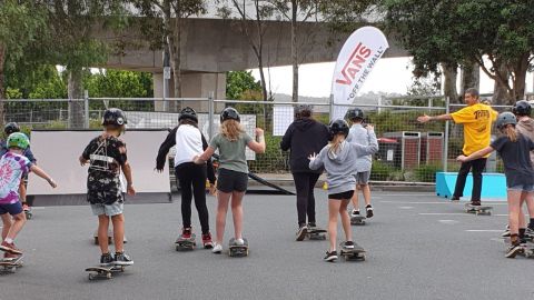 Group of children learn to ride skateboards.